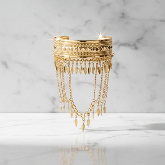 Bracelete boho em ouro posicionado verticalmente com parede de mármore